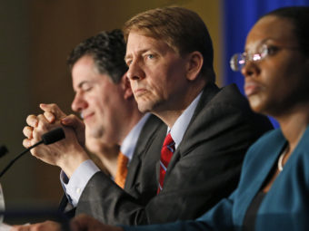 Consumer Financial Protection Bureau Director Richard Cordray, center, participates in a panel discussion in March. His agency is considering banning financial companies from routinely requiring consumers to sign away the right to sue. Steve Helber/AP