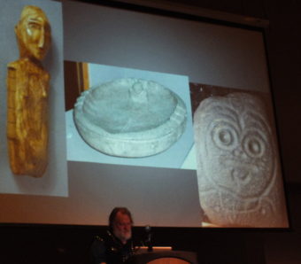 State curator of collections Steve Henrikson talks about key artifacts from the origins of Native peoples in Alaska. They include an ivory figurine from St. Lawrence Island, a stone oil lamp from Kodiak Island, and a petroglyph from Southeast Alaska. (Photo by Matt Miller/KTOO)