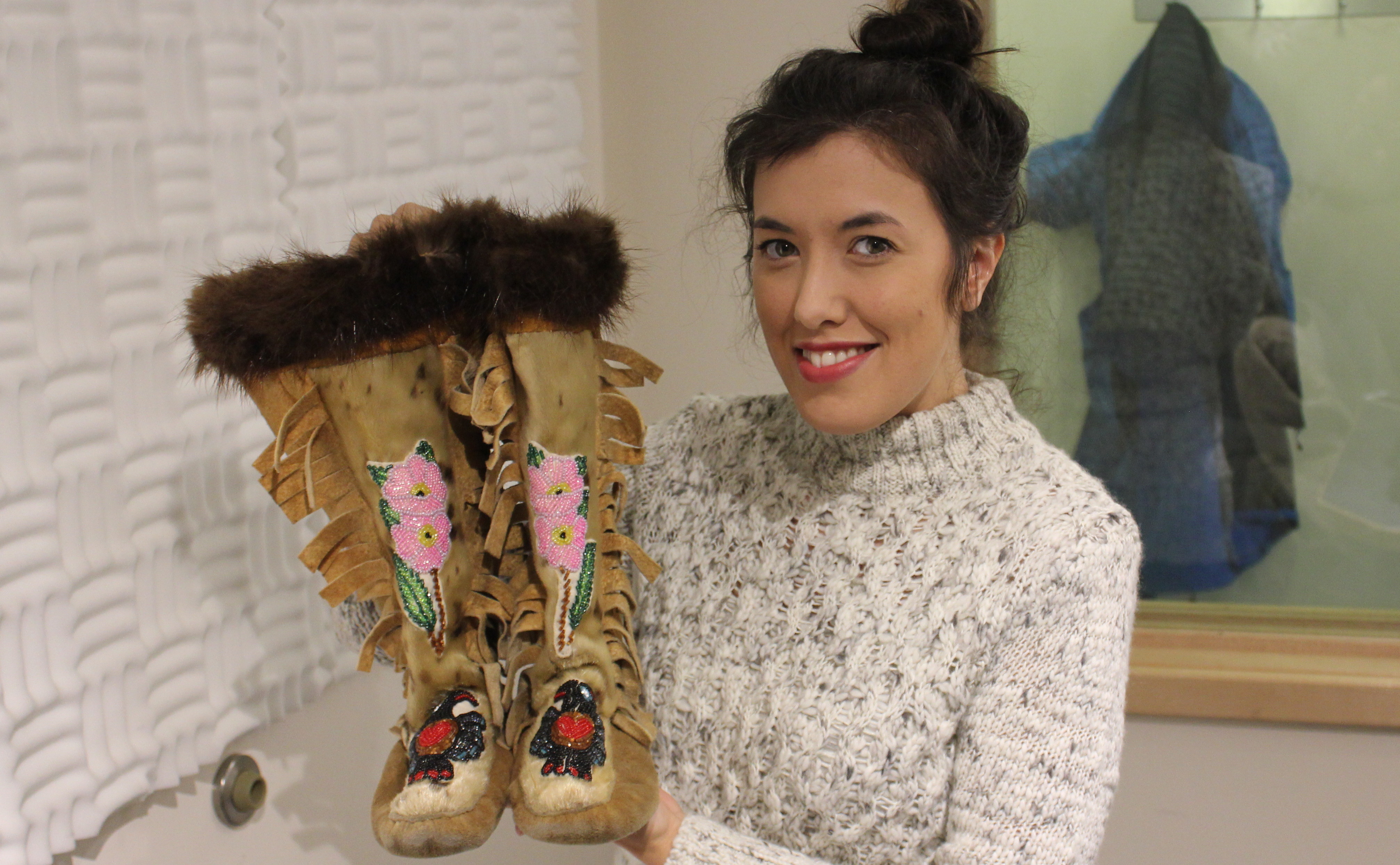 Crystal Nelson holds up a pair of moccasins passed down to her from her grandmother (Photo by David Purdy/KTOO)