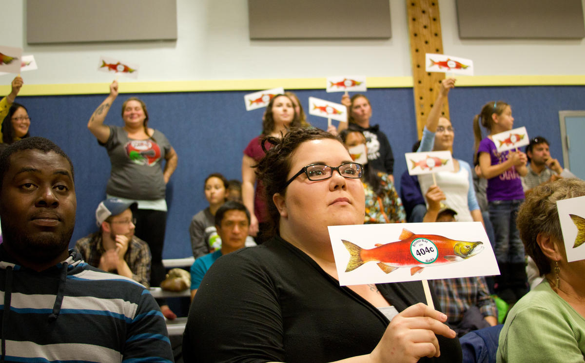 Crowd members hold salmon signs at a 2014 EPA hearing in Dillingham. (KDLG file photo)