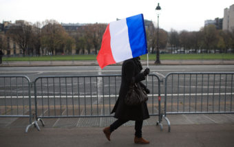 A woman carries a French flag during a ceremony in Paris on Friday honoring those killed in the Nov. 13 attacks. French President Francois Hollande has encouraged the French people to display flags, something they don't often do. Thibault Camus/AP