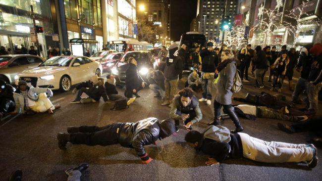 Demonstrators do push-ups Friday as others block motorists along Chicago's Michigan Avenue as they protest the shooting of Laquan McDonald who was killed by a police officer in 2014.