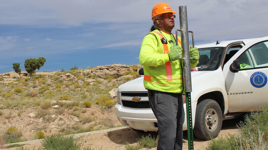 M.C. Baldwin, working for the Navajo Nation Rural Addressing Authority, installs a pair of street signs along BIA road 5020. (Photo by Carrie Jung/KJZZ)