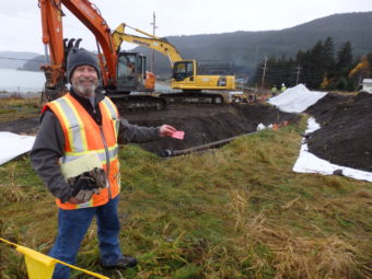 Army environmental protection specialist Brian Adams holds a flag that marks one of the soil testing sites at the fuel terminal admin area in October. (Photo by Emily Files/KHNS)
