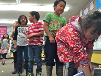 St. Paul students line up to stick their hands inside "blubber mitts" (Crisco-lined plastic bags) to learn how marine mammals stay warm in the cold Bering Sea. (Photo by John Ryan/KUCB)