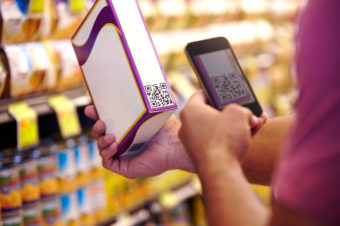 A man scans a voucher code in with his smartphone. Some food companies use labels like this to provide details about ingredients and manufacturing processes to consumers. iStockphoto