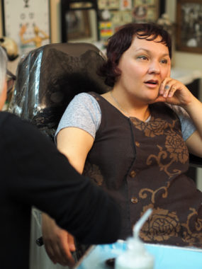 Holly Mititquq Nordlum, originally from Kotzebue, sits for a tattoo along her wrist from Greenlandic artist Maya Sialuk Jacobsen during a live demonstration of traditional tattooing techniques. (Photo by Zachariah Hughes/KSKA)