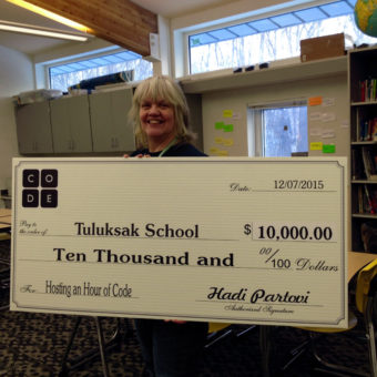 Katherine Garrison holding the check from Code.org inside her Tuluksak classroom. (Photo by Anna Rose MacArthur/KYUK)