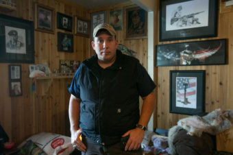 Hull stands in a room of his home decorated with photos of movie star John Wayne. "He was the only hero we had growing up. No one beats the Duke. You never heard about the Duke giving up," Hull says. Gordon King for NPR