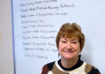 Southeast Senior Services Director Marianne Mills poses with a list of other organizations it works with. (Photo by Ed Schoenfeld,/CoastAlaska News)