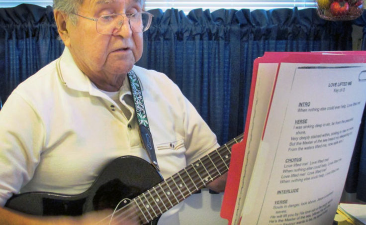 Ketchikan’s Fred John sings and plays a gospel song in his kitchen. He’s volunteered at Ketchikan’s prison and other locations. (Photo by Leila Kheiry/KRBD)
