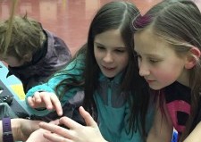 Payton Hammon, right, and Hailey Parmenter play with a hissing cockroach at the Stream Academy preview day. (Photo courtesy of Jennifer Howell)