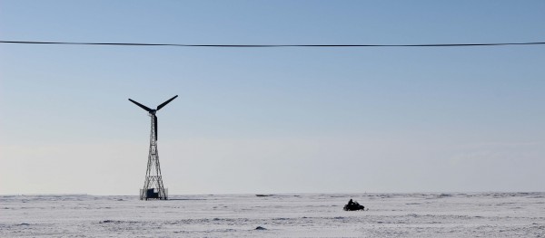 A snowmachine racing past one of Kwigillingok’s wind turbines. (Photo by Rachel Waldholz/APRN)
