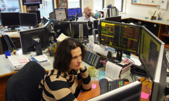 Alaska Permanent Fund Corp. employees use up to six computer screens each to monitor all things economic. Here, Fixed Income Portfolio Manager Maria (Masha) Skuratovskaya studies her screens. Jim Parise, director of investments is in the background, March 14, 2016. (Photo by Skip Gray/360 North)