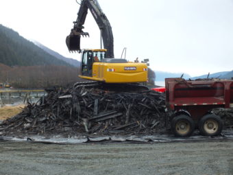 An excavator loads truck trailers with the woody remnants of the tug Challenger for the trip to the Juneau landfill.