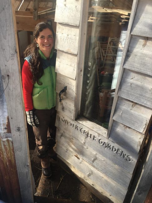 Emily Garrity peeks out from the door of her greenhouse at Twitter Creek Gardens on Ohlson Mountain outside Homer. (Photo by Daysha Eaton/KBBI)