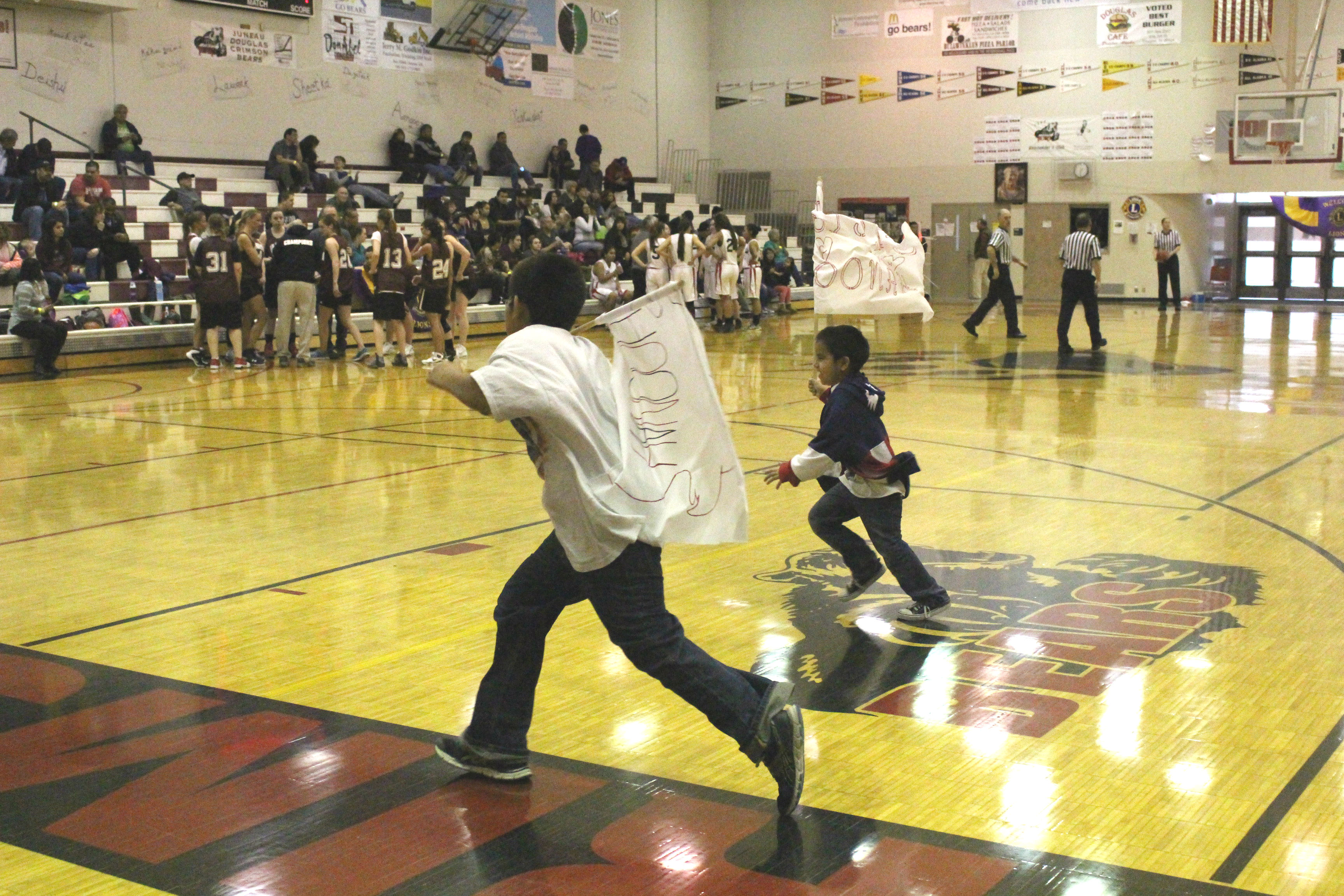 Kids run through court during a game break with homemade Hoonah flags. (Photo by Elizabeth Jenkins/KTOO