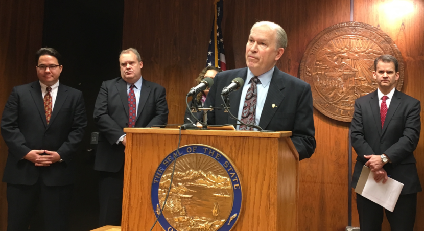 Gov. Bill Walker announces an administrative order on streamlining agencies. AIDEA Executive Director John Springsteen, AHFC CEO/Executive Director Bryan Butcher, Alaska Energy Authority Executive Director Sarah Fisher-Goad (partially obscured) and Administration Commissioner Sheldon Fisher are behind him. (Photo by Andrew Kitchenman)