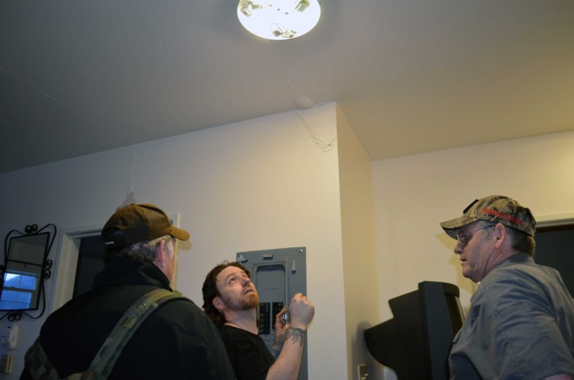 Resident Dennis Wharton, (left), and contractor David Phillips, (right), look on as Will Noel tests the electricity at the Channel View Apartments after one of the building's units caught fire Sunday afternoon. (Photo by Jennifer Canfield/KTOO)