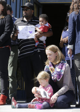 Alphonzo Jackson holds his 6-month-old son, Isaiah, behind Kim Turner and her daughter Adelaide Turner Winn during a rally supporting paid family leave at City Hall in San Francisco on Tuesday. (Jeff Chiu/AP)