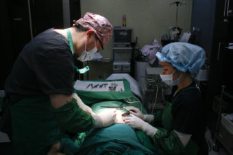 Dr. Hong Jung Geun, chief surgeon at Metro Plastic Surgery Clinic in Seoul (left), performs a pro-bono scar removal procedure on a former North Korean. Haeryun Kang/NPR