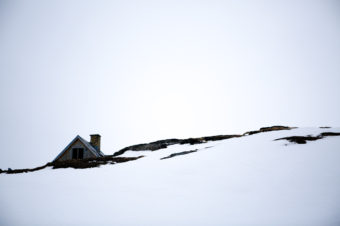 An abandoned house appears over a snow-covered hill in the old town of Kangeq, Greenland. John W. Poole/NPR