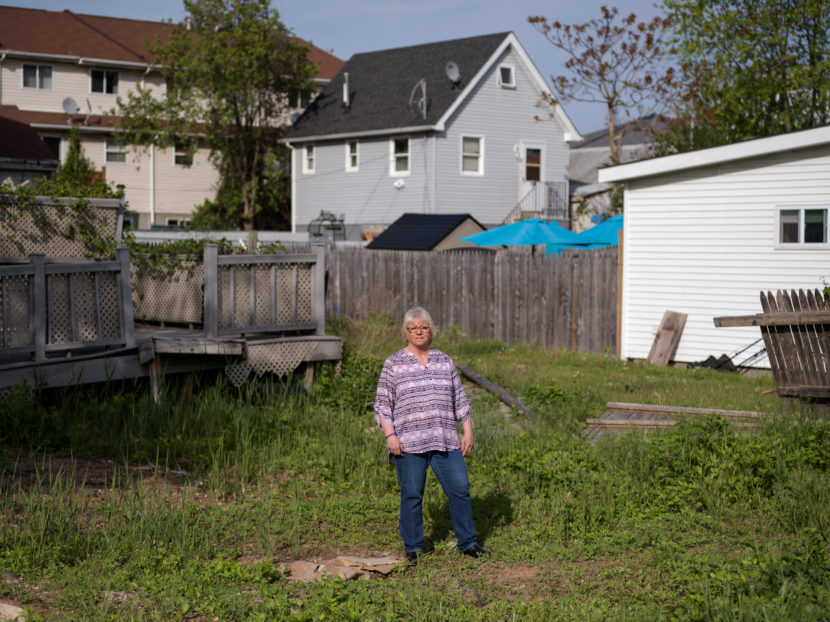 Like many other homeowners, Ann Marie Cianci — standing near her abandoned house on Staten Island, N.Y. — has been unable to move back home. After paying flood insurance for 32 years, she received only $60,000 out of her $250,000 policy. Bryan Thomas for NPR