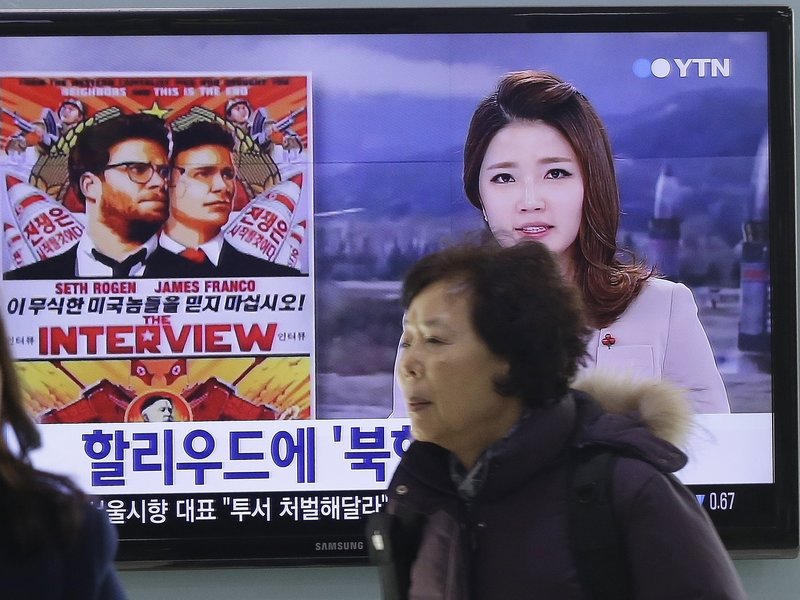 People walk past a TV screen showing a poster of Sony Picture's "The Interview" in a news report, at the Seoul Railway Station in Seoul, South Korea. The FBI says North Korea hacked into Sony Pictures computer systems as retribution for the film.