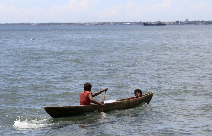 Two young men ride in a dug out canoe just off shore in Honiara, Solomon Islands, in 2012. Rick Rycroft/AP