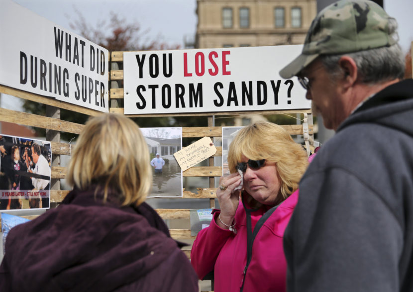 Sue Kenneally (center) wipes tears as she and other victims of Superstorm Sandy gather during a demonstration across from the statehouse in Trenton, N.J., in October 2015. More than three years after the 2012 storm, many residents are still not back in their homes. Mel Evans/AP