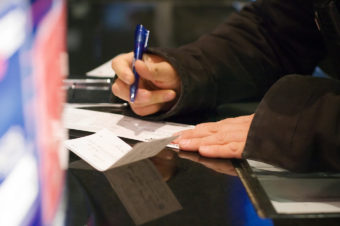 A man fills out a deposit slip at the bank.