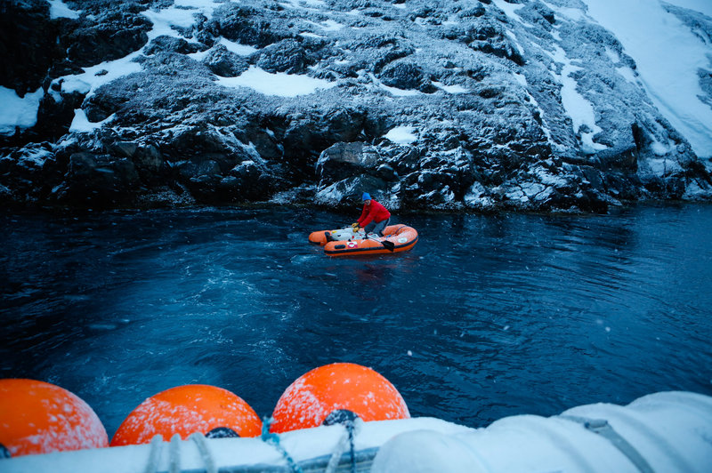 A visitor rows an inflatable dinghy loaded with fresh water to a small dock at the old settlement of Kangeq, Greenland. The village was officially shut down by the Danish government in the 1970s, and its residents were moved to a concrete apartment block in the capital city. John W. Poole/NPR