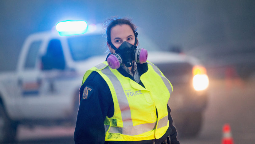 Smoke fills the air as a police officer stands guard at a roadblock along Highway 63 leading into Fort McMurray on Sunday. Scott Olson/Getty Images