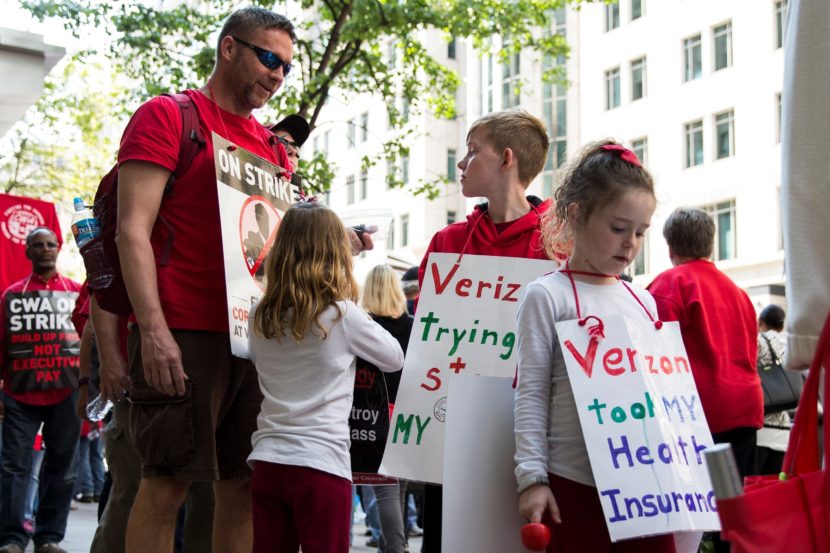 A Verizon worker on strike marches with his children and fellow employees on May 19. With no new contract, workers' health insurance expired at the end of April. Anadolu Agency/Getty Images