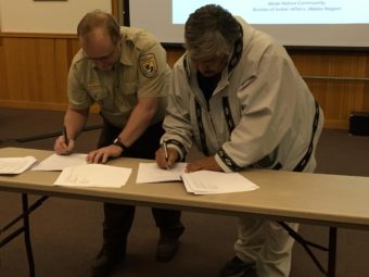 Chair Mike Williams Sr. signs the MOU with USFWS Yukon Delta Refuge Manager Ray Borne. (Photo by Charles Enoch/KYUK)