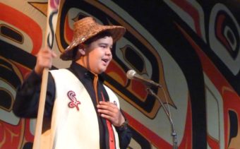 Youth Spokesman Matthew Wesley asks the Celebration audience for a Hoo-Ha cheer during the Taku Kwaan performance. (Photo by Ed Schoenfeld/CoastAlaska News)