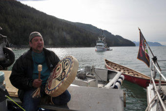 John Garcia plays a song for his fellow paddlers on Wednesday, June 8, 2016, near Juneau, Alaska. The One People Canoe Society group began the trip to Juneau from Angoon on June 2. Their landing on Douglas Island is the unofficial beginning of Celebration. (Photo by Rashah McChesney/KTOO)