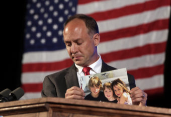 Mark Barden, father of a 7-year-old boy killed at the Sandy Hook Elementary School shooting in Newtown, Conn., holds a photo of his three children during his speech at the state's Democratic Convention, in Melville, N.Y., in 2014. Barden is one of 10 plaintiffs suing Remington Arms Co., the manufacturer of the assault rifle used in the mass murder. Richard Drew/AP
