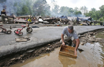 Mark Lester cleans out a box with creek water as he cleans up from severe flooding in White Sulphur Springs, W. Va., on Friday. Steve Helber/AP