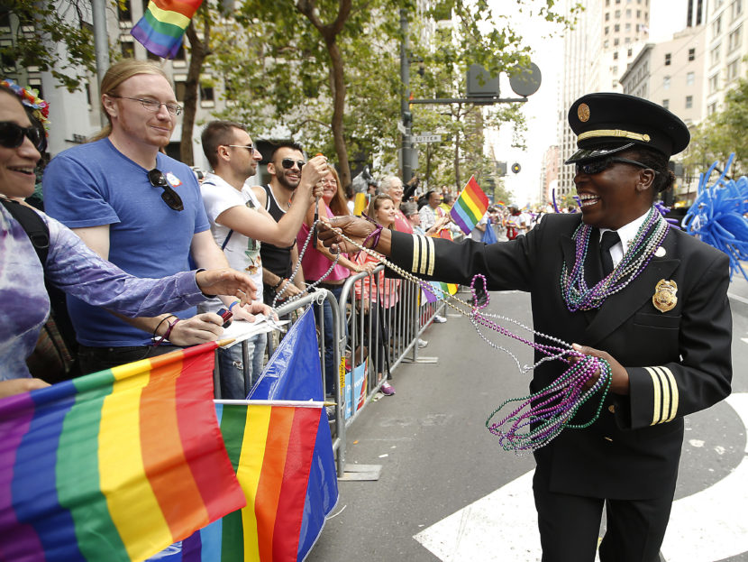 San Francisco Fire Department Deputy Chief Raemona Williams (right) passes out beaded necklaces to the crowd during the 2015 San Francisco Gay Pride Parade. Tony Avelar/AP