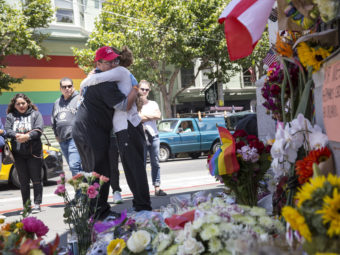 Larry Pascua hugs a friend Monday in San Francisco amid flowers and other items left as a memorial to those killed in the attack on a gay nightclub in Orlando, Fla. Andrew Burton/Getty Images