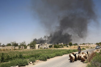 A young Syrian shepherd leads his flock on Tuesday as smoke billows from a farm following a reported airstrike in Sheifuniya, near the rebel-held town of Douma, east of Damascus. Abd Doumany/AFP/Getty Images