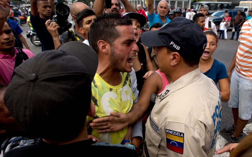 An angry man outside a grocery store argues with a policeman in Caracus, Venezuela, on June 8 amid the country's ongoing food shortages. After waiting for hours, customers began protesting, an increasingly common occurence in Venezuela, which is suffering a severe economic crisis. Fernando Llano/AP