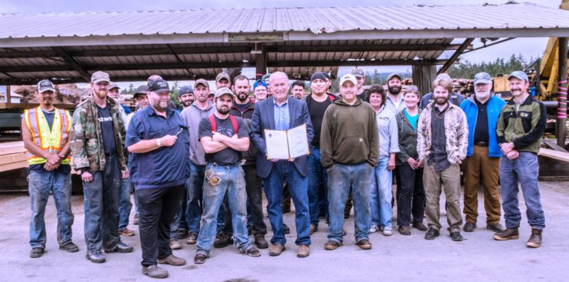 Gov. Bill Walker poses with mill workers July 16 at Viking Lumber in Klawock. He's holding a bill he signed that could increase the mill's timber supply. (Photo courtesy the governor's office)