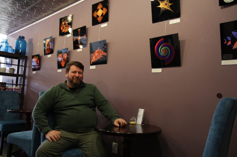 Bill Lee with some of his artwork at Boheme Coffee Lounge in Anchorage. (Photo by Graelyn Brashear/Alaska Public Media)