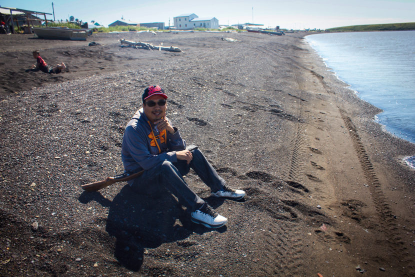 Bernard Abouchuk sits on the beach in Stebbins waiting for a seal. (Photo by Emily Russell/KNOM)