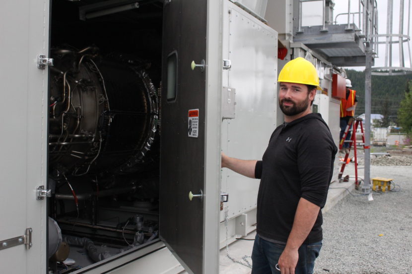 Bryan Farrell, an engineer at AEL&P, hold open the hatch the diesel fired turbine. (Photo by Elizabeth Jenkins/KTOO)