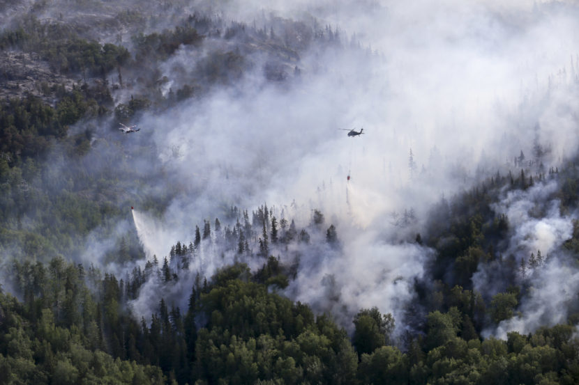 An Alaska Army National Guard UH-60 Black Hawk helicopter and a State of Alaska Division of Forestry helicopter dump several thousand gallons of water onto the McHugh Creek fire near Anchorage, July 20, 2016. (Public domain photo by photo by Staff Sgt. Balinda O’Neal Dresel/U.S. Army National Guard)