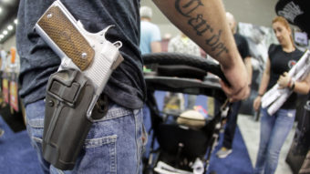 Donald Carder wears his handgun in a holster as he pushes his son, Waylon, in a stroller at the National Rifle Association convention in Louisville, Ky., in May. Attendees at the convention are permitted to carry firearms under Kentucky's open-carry law. (Photo by Mark Humphrey/AP)