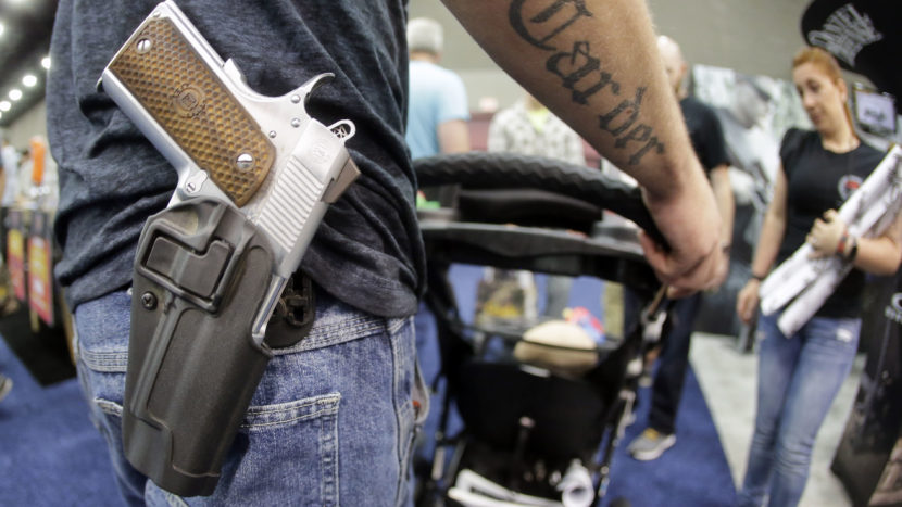 Donald Carder wears his handgun in a holster as he pushes his son, Waylon, in a stroller at the National Rifle Association convention in Louisville, Ky., in May. Attendees at the convention are permitted to carry firearms under Kentucky's open-carry law. (Photo by Mark Humphrey/AP)